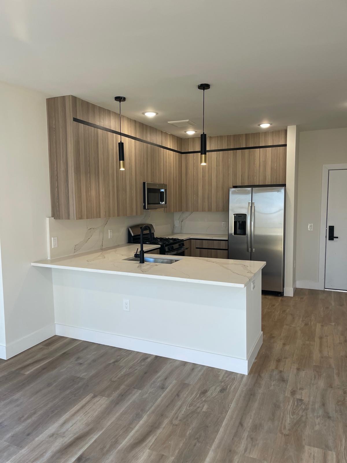 Modern apartment kitchen with quartz countertop and wood cabinetry